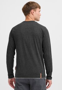 Grijs longsleeve shirt van zacht materiaal, met een ronde hals, geribbelde manchetten en een leren labeldetail aan de onderkant.