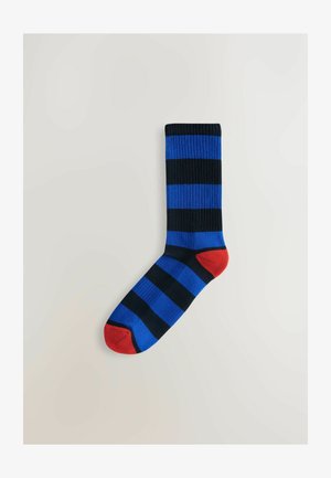 Gestreifte Socke in blau und schwarz mit geripptem Strick, roten Zehen und Fersen. Verfügt über horizontale Streifen in unterschiedlichen Breiten.