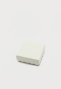 Μικρό κλειστό λευκό τετράγωνο κουτί με υφή στην επιφάνεια σε απλό λευκό φόντο.