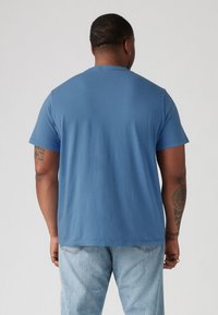 Blue cotton t-shirt with short sleeves, crew neck, and a smooth texture. Viewed from the back, featuring a relaxed fit and no visible logos.