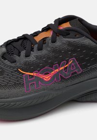Chaussure de course noire avec tige en mesh, accents violets et oranges, logo HOKA, semelle rembourrée et semelle extérieure texturée pour l'adhérence.