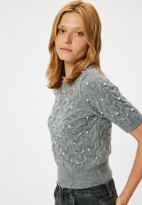 Grijs gebreid sweater met een kabelbreidesign, parelversieringen, korte mouwen en een getailleerde taille.