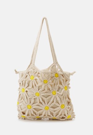 Beige gehäkelte Schultertasche mit Margeritenmustern mit gelber Mitte und einem inneren Stoffbeutel mit Kordelverschluss.