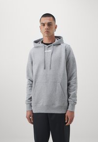 Hoodie grigio in cotone con tasca a marsupio, cappuccio con cordino e logo bianco sul petto. Texture liscia e vestibilità rilassata.