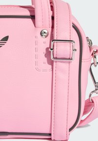 Ružová faux kožená kabelka s hladkým povrchom, strieborným kovovým prvkom, kontrastným prešívaním a detailom loga na povrchu.
