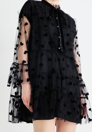Robe noire transparente avec motifs de cœurs en velours, volants superposés, boutons en perles et longues manches bouffantes nouées aux poignets avec de grands nœuds.