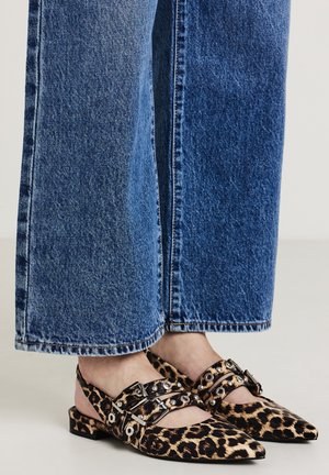 Ballerine con stampa leopardata, punte affusolate, cinturini neri, finiture in argento, abbinate a jeans blu a gamba larga. Motivo animale testurizzato.