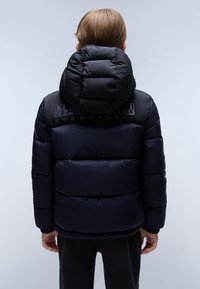 Dítě v tmavě modré a černé zateplené zimní bundě s kapucí, z pohledu zezadu na jednoduchém pozadí.