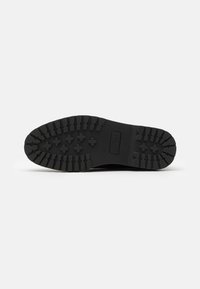 Black rubber sneaker outsole featuring a rugged tread pattern with deep grooves and circular accents. Marked with "ZIGN" and size 42.