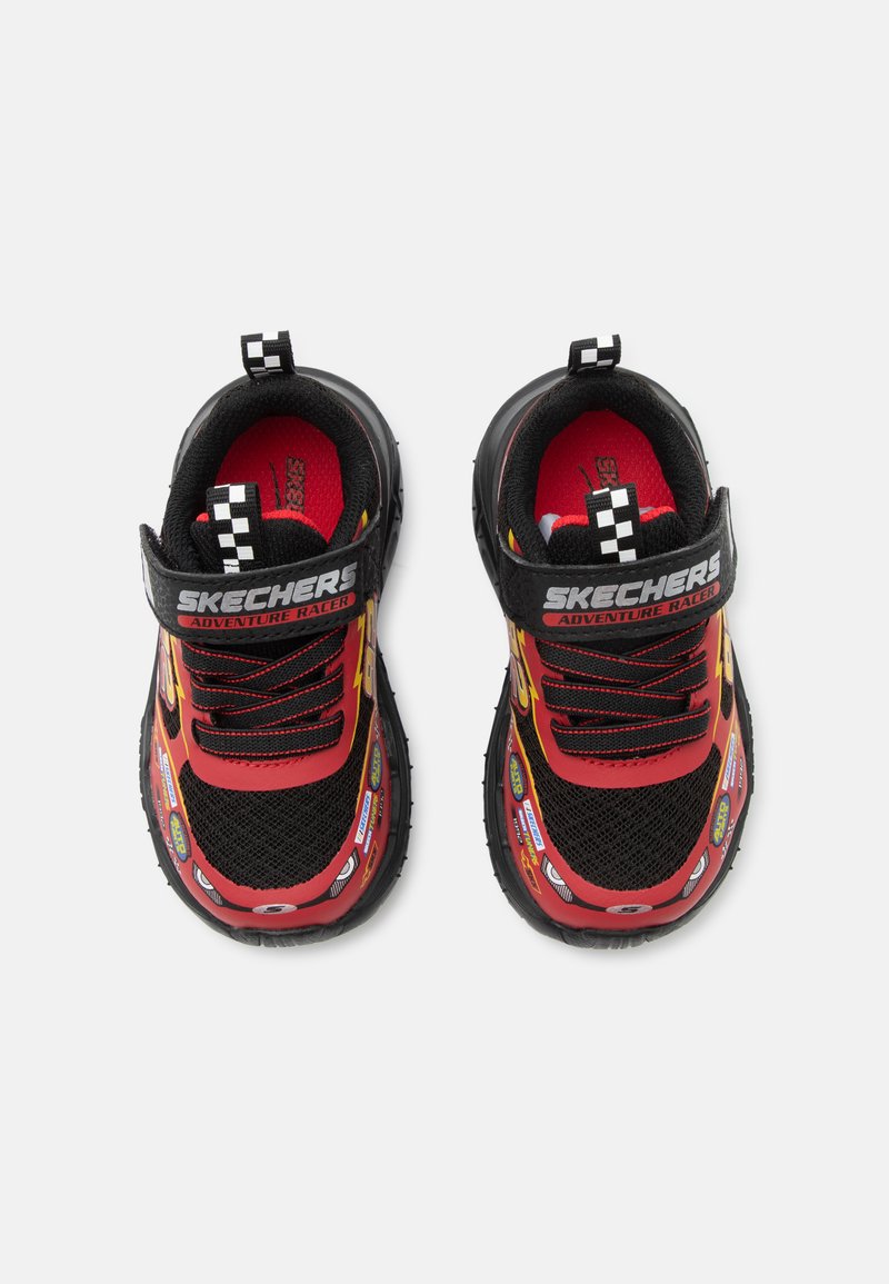 Παιδικά μαύρα και κόκκινα sneakers Skechers με την ετικέτα «Adventure Racer», καρό ταινίες για τράβηγμα, κεραυνός και αυτοκόλλητα με θέμα τους αγώνες.