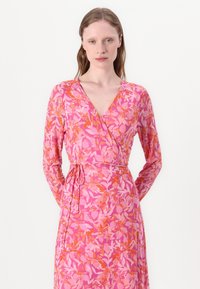 Rochie înfășurată de culoare roz, cu un model floral cu frunze portocalii. Mâneci lungi și un detaliu cu șiret la talie completează designul. Textură moale a materialului.