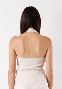 Top beige senza spalline, aderente, realizzato in tessuto morbido, con un collo pulito e una silhouette snella caratterizzata da una leggera lucentezza.