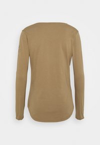 Långärmad skjorta i ljusbrun färg, med rundad halsringning och mjuk textur, med minimal detaljering på vänster ärm.