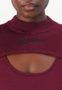 Bordeaux trui met geribbelde colontwerp, met een uitsnijding en geborduurd "KARL LAGERFELD JEANS" logo op de borst.