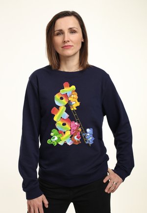 Navy sweatshirt med et multicolor grafisk motiv af tegneserie-bjørne, der klatrer op ad en stige, med fede, regnbuefarvede bogstaver i designet.