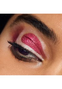 Stängd öga med djärv rosa glitterögonskugga på ögonlocket, mjuk vit shimmer nära den inre ögonvrån och mörk mascara på ögonfransarna.