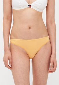 Żółta bawełniana bielizna z koronkowym wykończeniem, z białym paskiem "TOMMY HILFIGER". Prosty, klasyczny design idealny na codziennie noszenie.