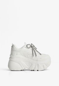 Vita plattformssneakers med texturerat övre, böjd design och silverpärlor som skosnören. Tjock, ribbad sula för ökad höjd och stabilitet.