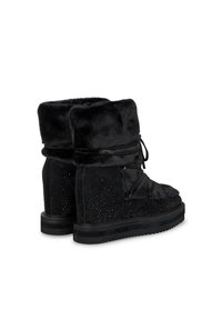 Botas negras de tobillo con parte superior de pelo sintético, volantes decorativos y acentos con tachuelas. Suela de goma con un acabado texturizado.