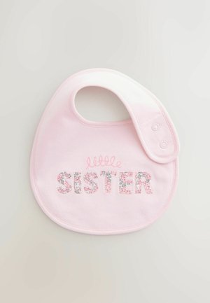 Ružová bavlnená podbradník s okrúhlym tvarom, zdobená výšivkou "SESTRA" s kvetinovým vzorom a zapínaním na patentku na krku.