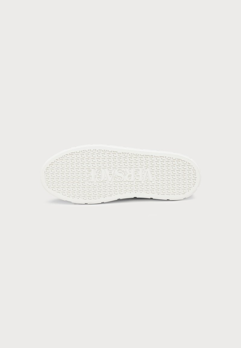 White shoe sole with a textured geometric pattern and the word "VERSACE" embossed in the center.