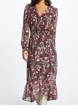 Kvinde iført en kjole med lange ærmer og ankellængde med et paisley-mønster i burgunder, hvid og blå samt en taljeret pasform.