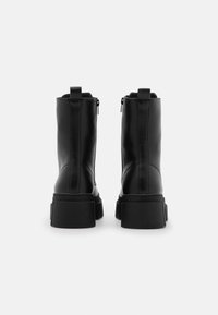 Black leather ankle boots with a smooth texture, featuring a chunky sole, side zippers, and pull tabs for ease of wear.