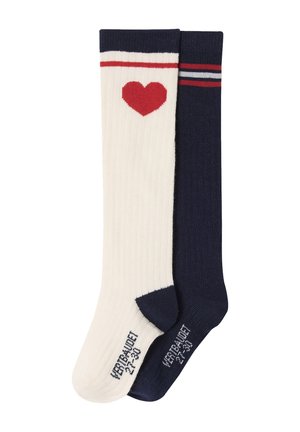 Ein weißer Socken mit einem roten Herz und rotem Streifen, kombiniert mit einem marineblauen Socken, der oben rote und weiße Streifen aufweist.