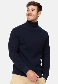 Granatowy sweter z dzianiny z wysokim kołnierzem, ściągaczami na mankietach i korpusie. Posiada fakturowany materiał oraz dopasowany fason. Idealny na chłodne dni.