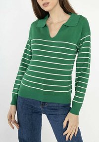 Pull �à rayures vertes avec un col en V, fabriqué en tissu doux, avec des rayures horizontales blanches et des poignets côtelés.