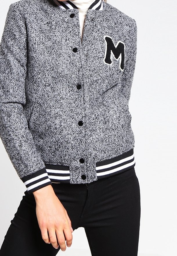 Grå og sort tekstureret varsity-jakke med hvide striber på kraven og manchetterne, der har et sort bogstav "M" patch på fronten.