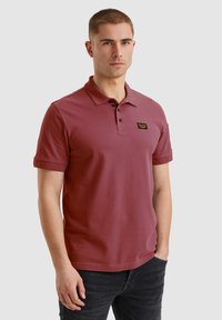 Bordo polo majica s tri gumbe na sprednjem delu, kratkimi rokavi in logotipom na prsih. Narejena iz gladkega, zračnega materiala.