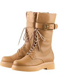 Tan leren gevechtslaarzen met een hoge schacht, vetersluiting aan de voorkant, zijrits, robuuste zool en een verstelbare band met metalen hardware.