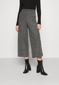 Szare, nakrapiane, szerokie spodnie z elastycznym pasem, zestawione z czarnymi botkami na niskim słupku.