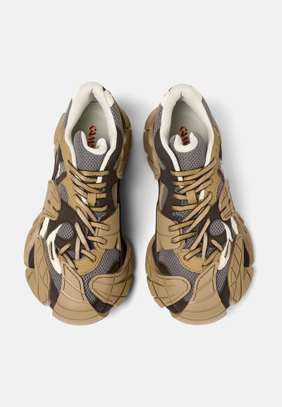 Zapatillas con una parte superior de malla en gris y marrón, acentuadas con superposiciones en beige, suelas texturizadas y cordones estándar.