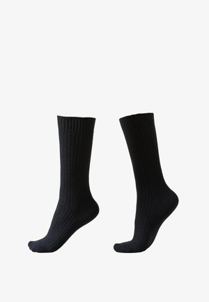 Chaussettes noires côtelées de longueur mi-mollet, avec un bord élastique et une texture lisse. Le design est simple avec des lignes verticales uniformes.