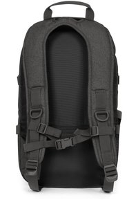 Šedý látkový batoh s polstrovaným zádovým panelem, nastavitelnými popruhy a přezkami. Hladký povrch, strukturovaný tvar a detail síťové kapsy.