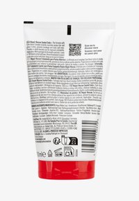 Tube blanc avec une base rouge, contenant 100 ml de traitement capillaire. Contient la liste des ingrédients et les instructions d'utilisation en plusieurs langues. Code QR inclus.