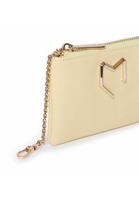 Portefeuille en cuir jaune avec une texture lisse, comportant une chaîne dorée et un accent métallique en forme de cœur sur le devant.