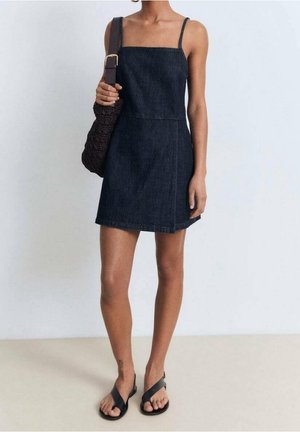 Dunkelblaues Denim-Kleid mit dünnen Trägern, A-Linie und einer Länge bis zur Mitte des Oberschenkels. Die Accessoires umfassen eine braune Tasche und schwarze Flip-Flops.