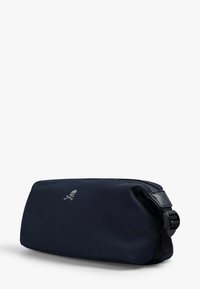 Funda blanda navy con cierre de cremallera, que presenta un pequeño logo de calavera plateado y una correa negra texturizada. Diseño duradero y compacto.