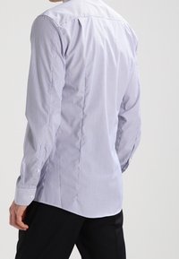 Ljusblå randig skjorta med knappar och långa ärmar, med en standardkrage och en mjuk blandning av bomull. Bakvyn visar en skräddarsydd passform.