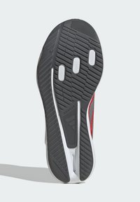 Black rubber shoe sole with patterned treads, featuring white accent sections and a gray midsole, labeled "ADIDAS" for brand identification.
