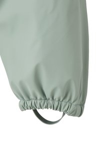 Pale green waterproof pant leg with elasticated cuff and ankle stirrup strap for secure fit.