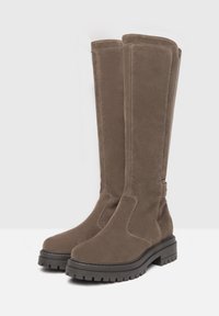 Brown knee-high boots made of soft suede, feature a chunky black sole and subtle stitching details. Sleek design with a rounded toe.