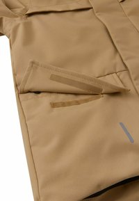 Beige Jackenstoff mit glatter Textur, ausgestattet mit einer Klappentasche und grauen Akzentstreifen. Klettverschluss an der Tasche.