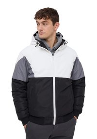 Giacca puffer da uomo con una sezione superiore bianca, pannelli sulle spalle grigi e una parte inferiore nera solida, dotata di zip frontale e cappuccio.