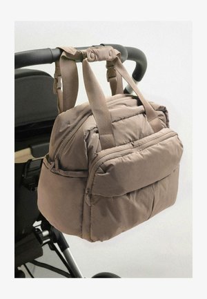 Geantă bej căptușită cu două bretele din material textil ajustabile, un buzunar frontal cu fermoar și o textură fină, montată pe mânerul unui cărucior.