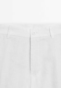 Weiße Leinenhose mit Knopfverschluss, flachem Vorderteil und subtiler texturierter Oberfläche. Einfaches Design ohne sichtbare Muster oder Akzente.