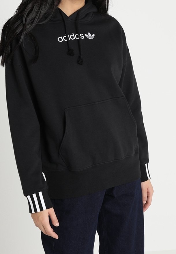 Mustapaitainen huppari, jossa valkoinen "adidas"-logo ja pieni trefoil. Sisältää etutaskun ja valkoiset raidat hihoissa.